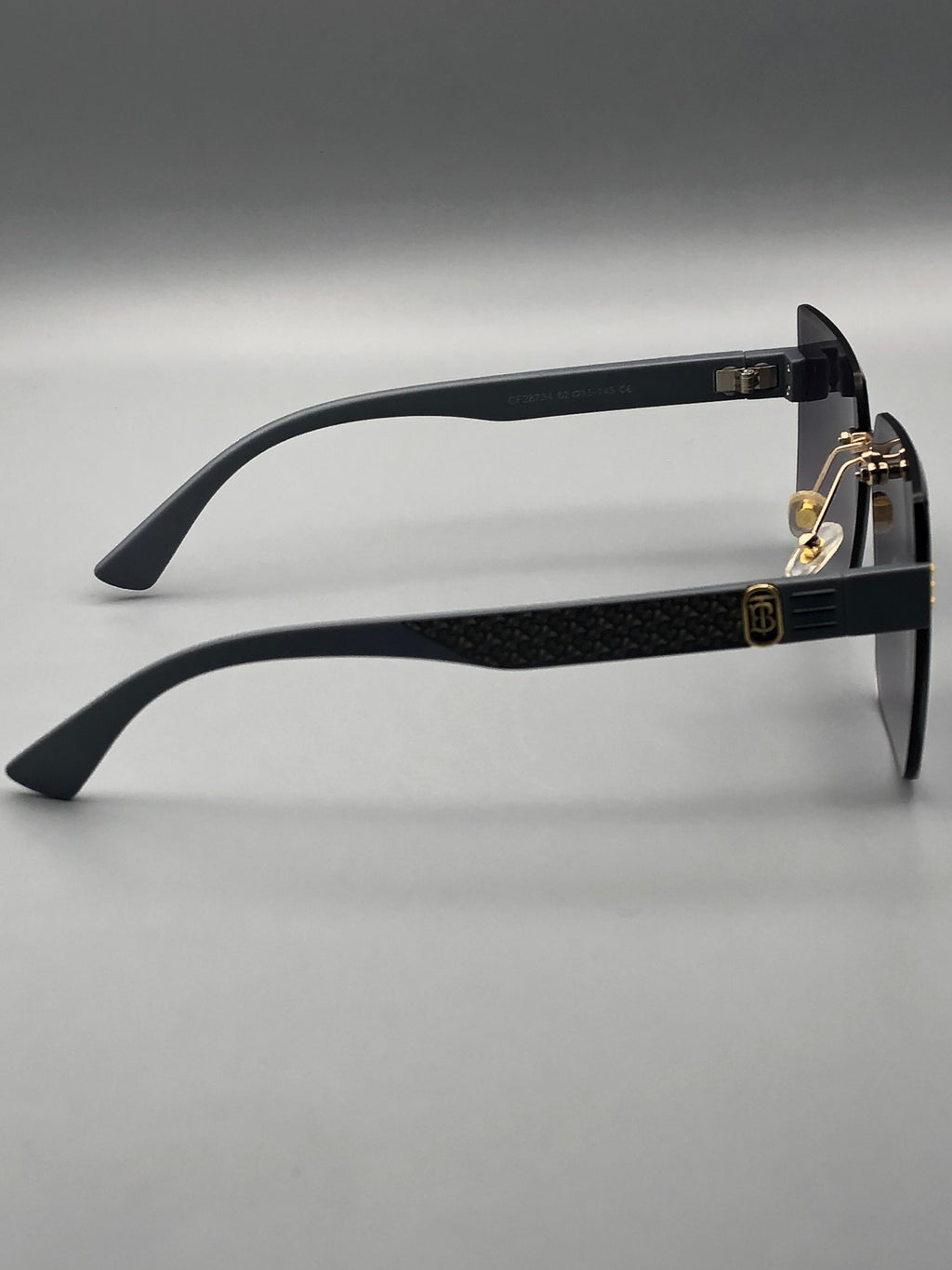 Black sunglasses with gold accents on a gray background